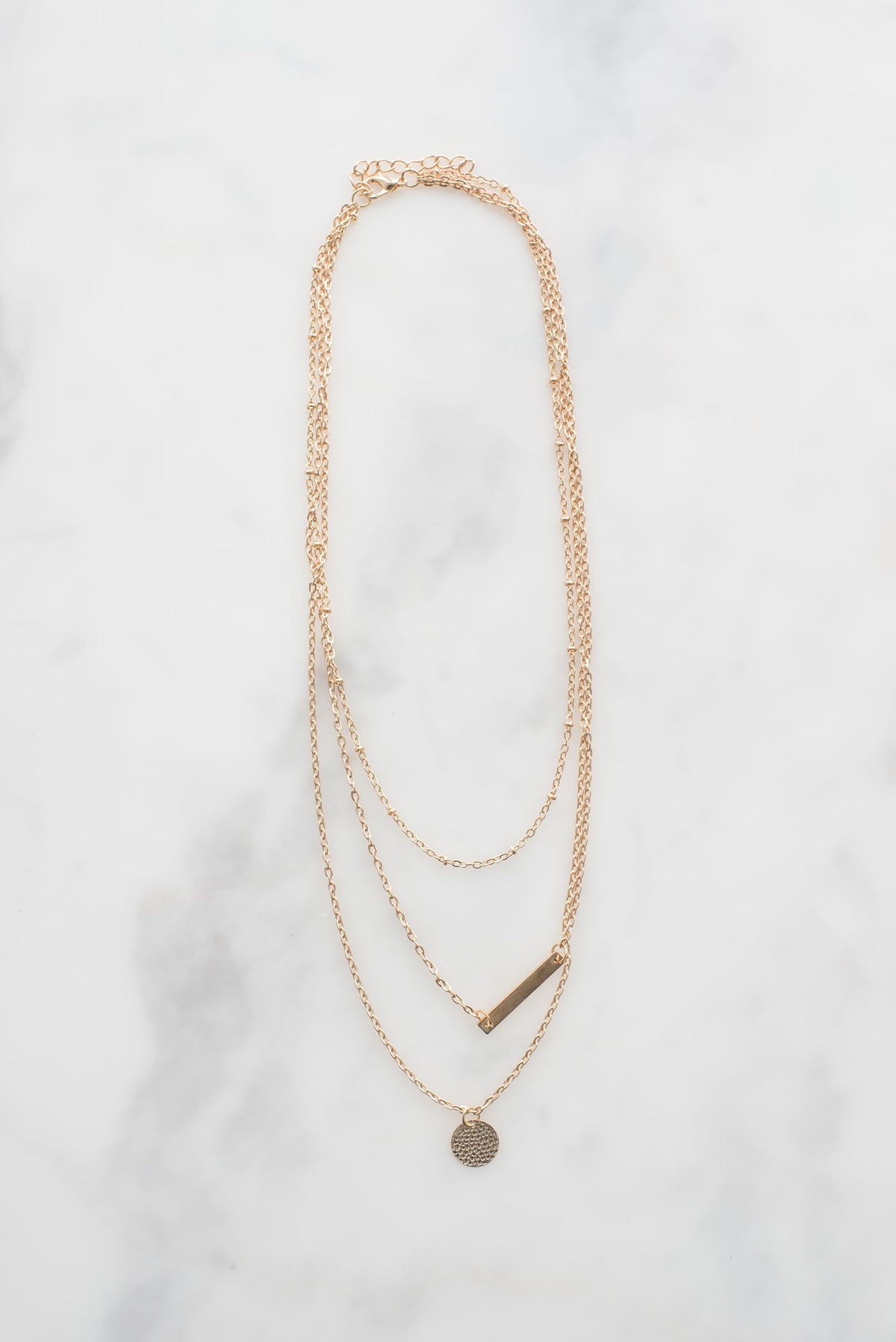 Pearl drop pendant on a fine chain, on marble